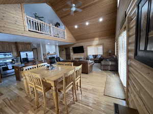 Dining area featuring log walls, wood ceiling, light wood-type flooring, and ceiling fan