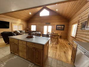 Kitchen with rustic walls, light wood-style floors, a kitchen island, and dishwasher