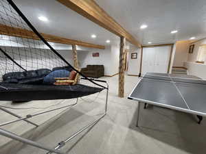Recreation room with recessed lighting, light colored carpet, baseboards, and a textured ceiling