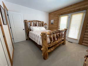 Bedroom featuring a textured ceiling, light colored carpet, visible vents, and rustic walls