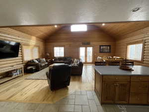 Living area featuring rustic walls, french doors, a textured ceiling, and wood-type flooring