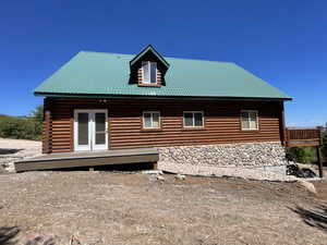 Exterior space featuring stone siding, log exterior, french doors, and metal roof