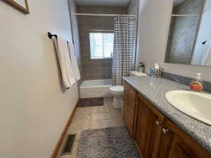 Bathroom featuring visible vents, baseboards, toilet, shower / bath combo, and vanity