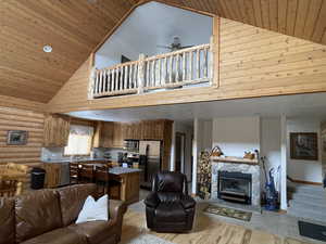 Living area featuring wood ceiling, a ceiling fan, high vaulted ceiling, and light wood-style flooring