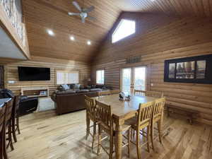 Dining room with wooden ceiling, light wood-style flooring, french doors, and high vaulted ceiling