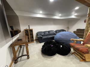 Carpeted living room with recessed lighting, baseboards, and a textured ceiling