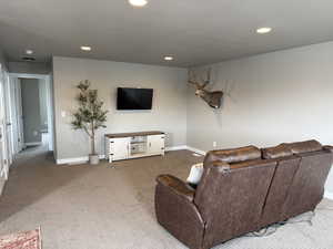 Living area with recessed lighting, a textured ceiling, baseboards, and carpet floors