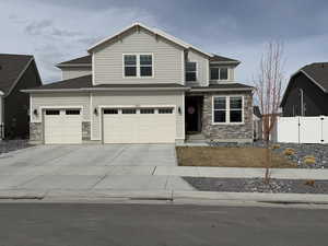 View of front of home featuring fence, concrete driveway, a garage, stone siding, and a gate