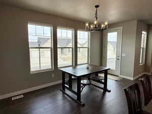 Dining area featuring visible vents, baseboards, a notable chandelier, and dark wood-style flooring