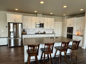 Kitchen with a sink, dark countertops, dark wood-style flooring, and stainless steel appliances