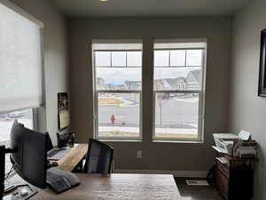 Office with visible vents, dark wood-type flooring, and baseboards