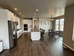Kitchen featuring visible vents, dark countertops, stainless steel appliances, an inviting chandelier, and dark wood-style flooring