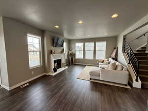 Living room with stairway, dark wood-style floors, visible vents, and a wealth of natural light