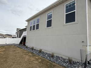 View of side of property with fence, a lawn, and stucco siding