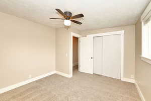 Unfurnished bedroom with carpet flooring, ceiling fan, a textured ceiling, and baseboards