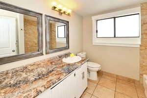 Full bathroom with vanity, tile patterned floors, and toilet