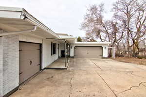 View of property exterior with brick siding, concrete driveway, and a garage