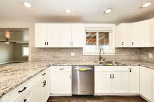 Kitchen with a sink, stainless steel dishwasher, ceiling fan, and white cabinetry