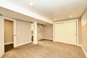 Finished basement with baseboards, a textured ceiling, and carpet