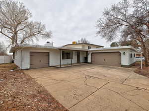 View of front facade with brick siding, an attached garage, concrete driveway, and fence