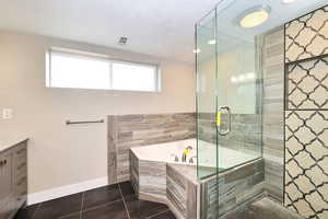 Full bath featuring vanity, baseboards, a stall shower, tile patterned flooring, and a bath