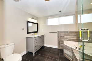 Full bath featuring tile patterned floors, toilet, a shower stall, baseboards, and vanity