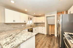 Kitchen with tasteful backsplash, light stone counters, dark wood-style flooring, appliances with stainless steel finishes, and a sink