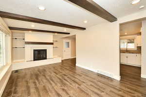 Unfurnished living room with a sink, visible vents, a healthy amount of sunlight, and dark wood finished floors