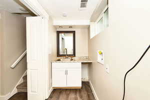 Bathroom featuring visible vents, baseboards, wood finished floors, and vanity