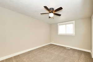 Spare room featuring baseboards, carpet floors, and a textured ceiling