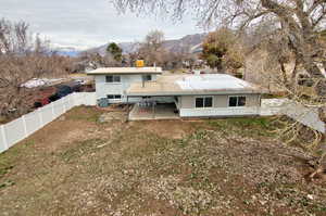 Rear view of property featuring a mountain view, a patio, a fenced backyard, and a chimney