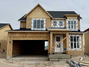 Unfinished property featuring an attached garage and a shingled roof