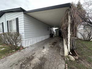 View of side of property featuring an attached carport and driveway