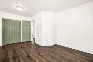 Unfurnished bedroom featuring dark wood-style flooring, baseboards, and a closet