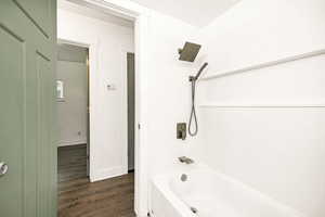 Bathroom with wood finished floors and bathing tub / shower combination