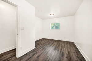 Unfurnished room with dark wood-style floors and baseboards