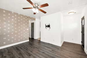 Spare room with dark wood-style flooring, a ceiling fan, baseboards, and a smoke detector