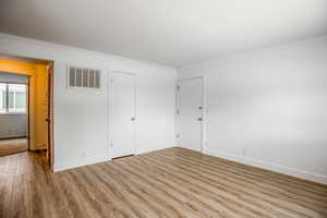 Empty room with visible vents, crown molding, baseboards, and wood finished floors