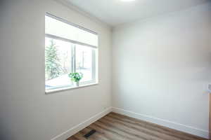 Spare room featuring crown molding, visible vents, baseboards, and light wood-type flooring