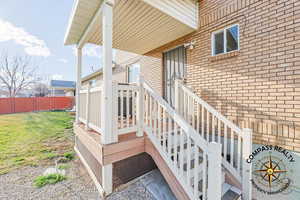 Back porch goes in 1st level laundry/mud room Entrance to property featuring a yard, brick siding, and fence