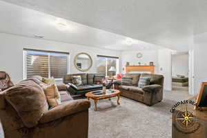 Carpeted living room featuring visible vents and a textured ceiling