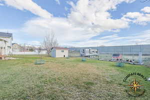 View of yard with a storage shed, an outdoor structure, and fence
