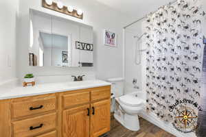 Primary Bathroom featuring vanity, shower / bathtub combination with curtain, toilet, and wood finished floors