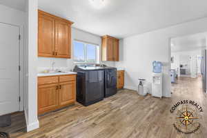 Laundry room featuring light wood-style flooring, cabinet space, independent washer and dryer, and a sink