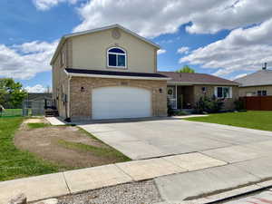 Traditional-style house featuring a garage, fence, a front lawn, brick siding, and driveway