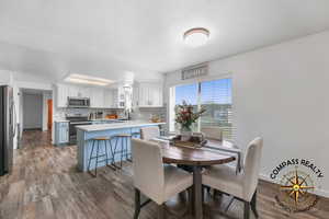 Dining area with a textured ceiling, baseboards, and wood finished floors
