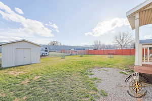 View of yard with a storage unit, an outdoor structure, and fence
