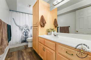 Full Bathroom featuring vanity, a shower with shower curtain, wood finished floors, visible vents, and toilet