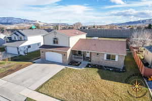 View of front of home featuring a porch, fence, a mountain view, a front yard, and a garage