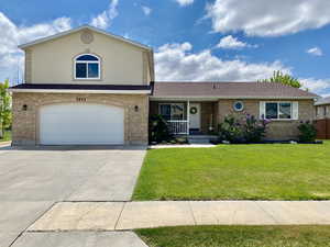 View of front of property with a porch, an attached garage, a front lawn, and brick siding